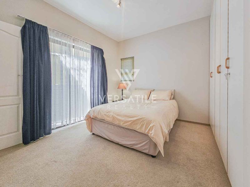 A well-maintained bedroom featuring neutral carpeting, built-in floor-to-ceiling cupboards, and a sliding glass door providing access to the exterior.