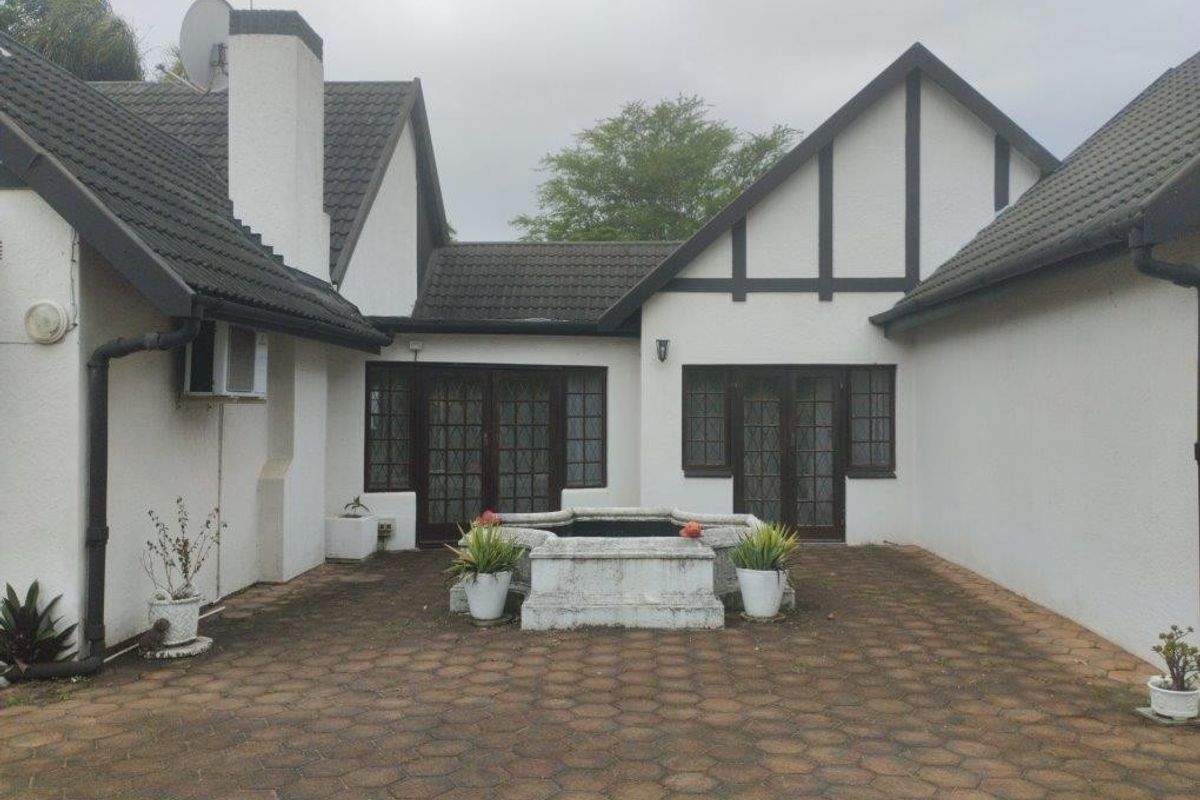 Rear courtyard area featuring paved flooring, a central stone water feature, and access to the home via multiple sets of french doors.