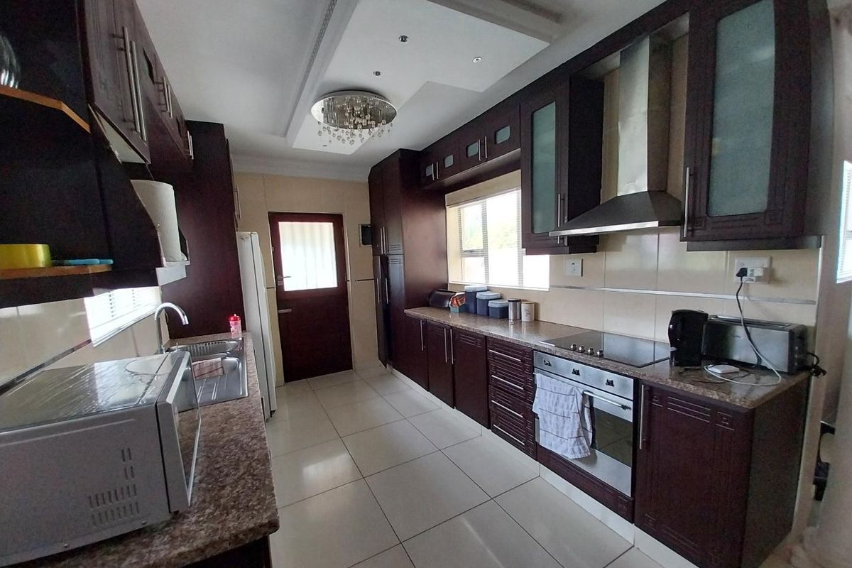 A functional kitchen featuring dark wood cabinetry, granite countertops, stainless steel appliances, and tiled flooring with recessed ceiling lighting.