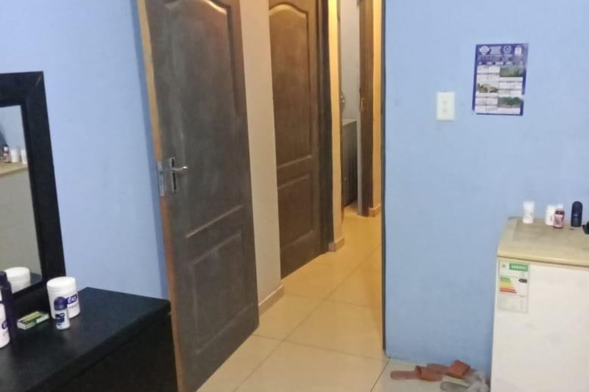 A bedroom interior featuring tiled flooring and access to an adjacent hallway through internal doors.