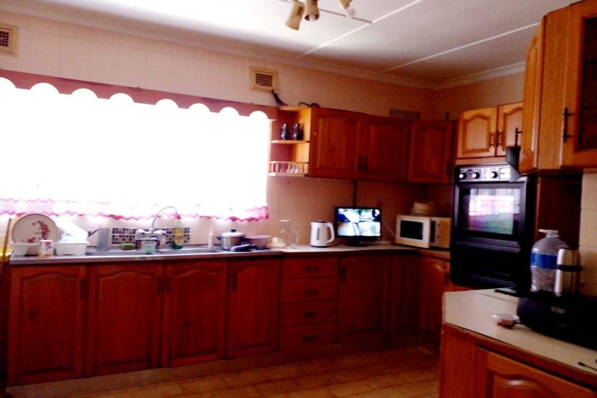A dated kitchen featuring traditional wooden cabinetry, a built-in oven, and tiled surfaces, offering significant potential for a modern renovation.