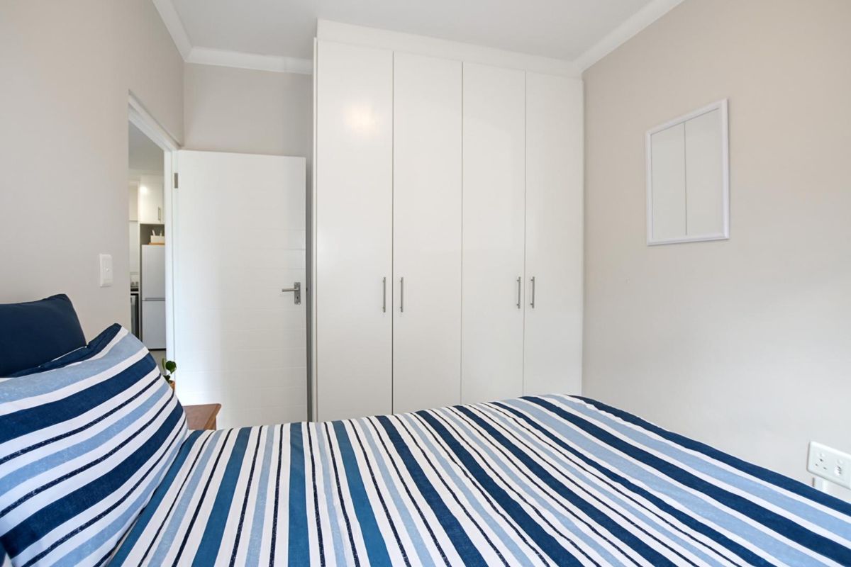 A bright bedroom featuring built-in white cabinetry and neutral wall finishes, offering a clean and functional living space.