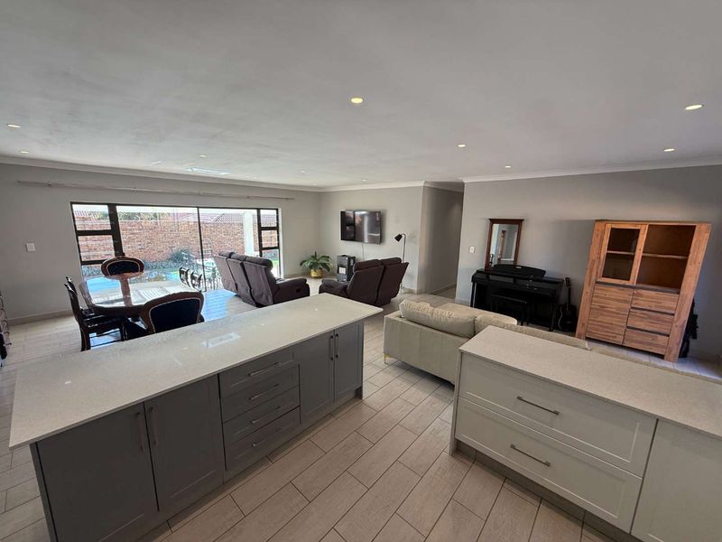 Spacious open-plan living area featuring a modern kitchen island with quartz countertops, recessed lighting, and large sliding doors leading to the outdoor space.