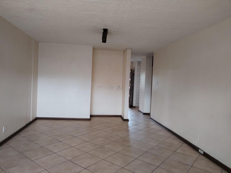 A spacious, empty living area featuring neutral tiled flooring and clean walls, providing a versatile blank canvas for interior design and furniture placement.
