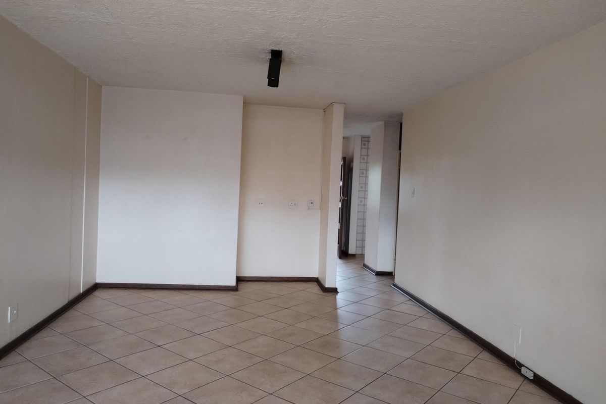 A spacious, empty living area featuring neutral tiled flooring and clean walls, providing a versatile blank canvas for interior design and furniture placement.
