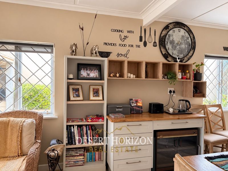 A functional kitchen area featuring built-in cabinetry, a wooden countertop, and an integrated under-counter wine cooler, complemented by crown molding and security-barred windows.