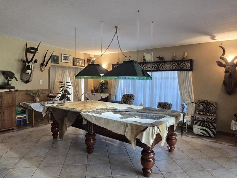 Spacious living area featuring tiled flooring and dual pendant lighting, currently utilized as a recreational space.