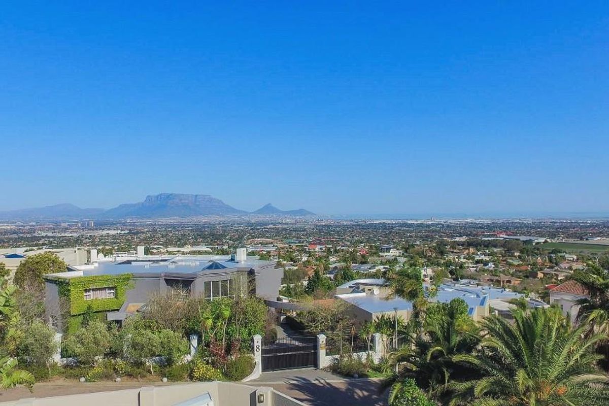 Elevated aerial view showcasing the property's expansive landscape, surrounding neighbourhood, and prominent mountain vistas in the distance.