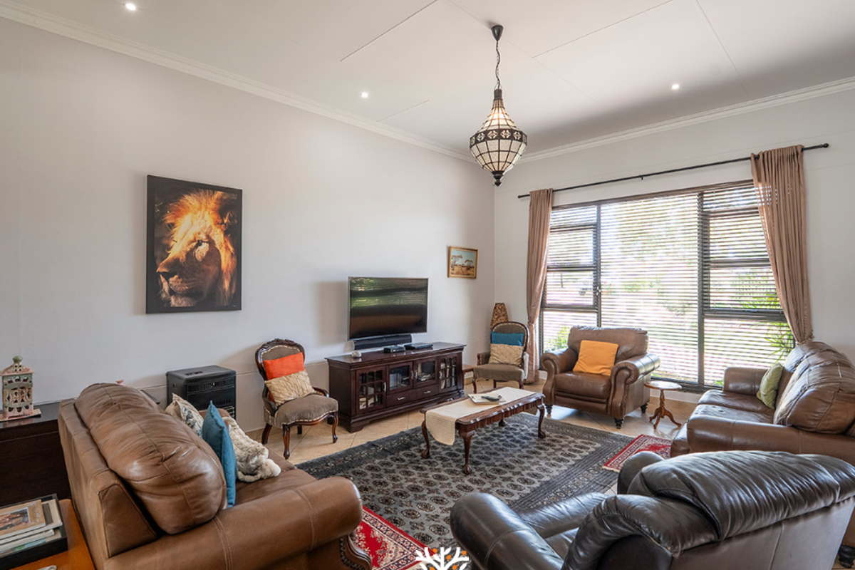Spacious living room featuring tiled flooring, recessed ceiling lighting, and large windows with horizontal blinds, providing ample natural light.
