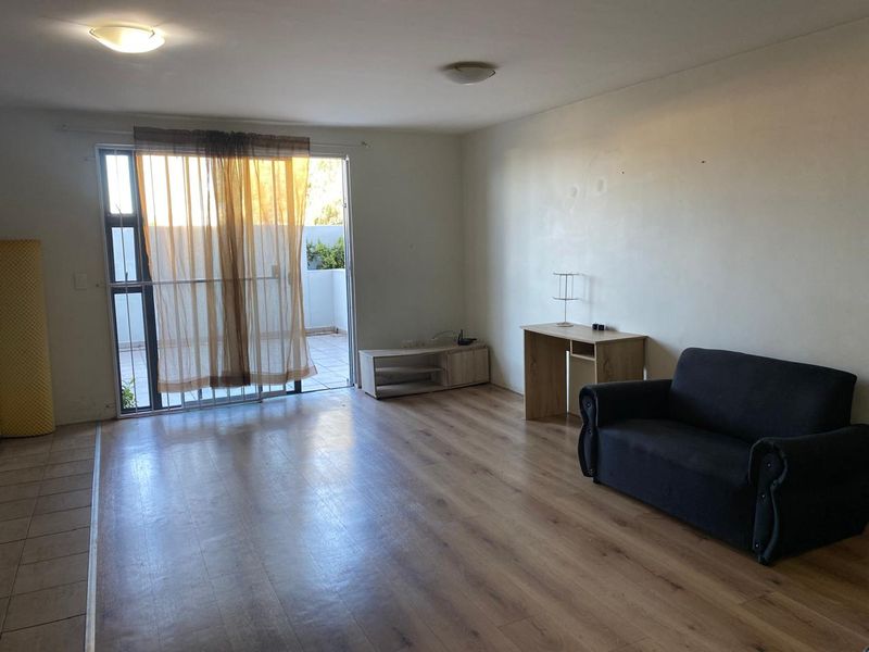 Spacious living area featuring laminate flooring and a large sliding glass door providing access to an outdoor patio space.