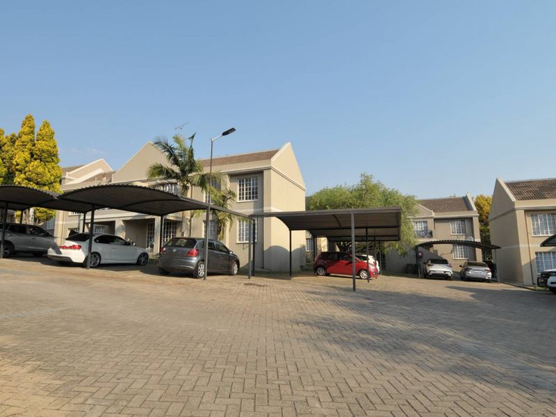 Exterior view of an apartment complex featuring paved parking areas and covered carports for residents.
