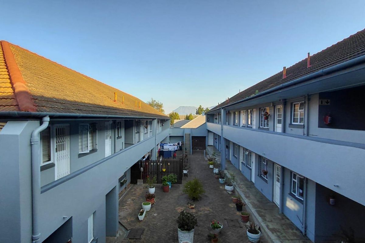 An elevated view of the apartment complex courtyard, featuring external walkways, tiled roofing, and access to multiple residential units.