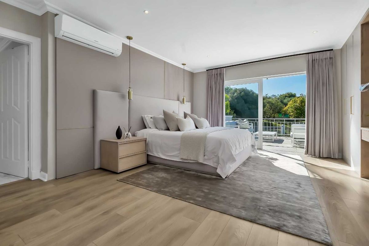 Spacious bedroom featuring light wood flooring, built-in cabinetry, wall-mounted air conditioning, and sliding glass doors leading to a private balcony.