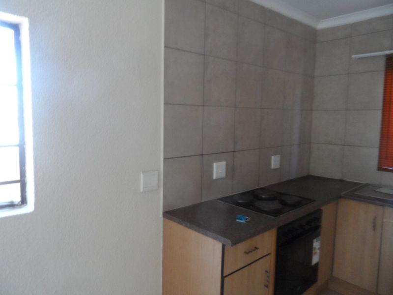 A functional kitchen area featuring built-in cabinetry, a laminate countertop, an integrated electric hob, and a built-in oven with tiled splashback.