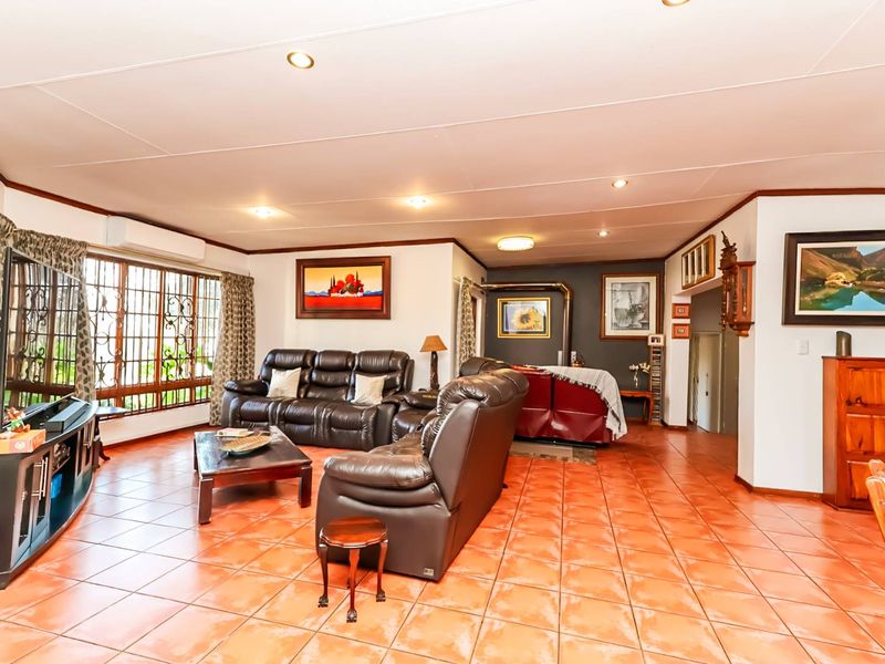 Spacious living room featuring terracotta-style tiled flooring, recessed lighting, a built-in wood-burning fireplace, and a wall-mounted air conditioning unit.
