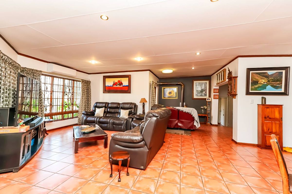 Spacious living room featuring terracotta-style tiled flooring, recessed lighting, a built-in wood-burning fireplace, and a wall-mounted air conditioning unit.