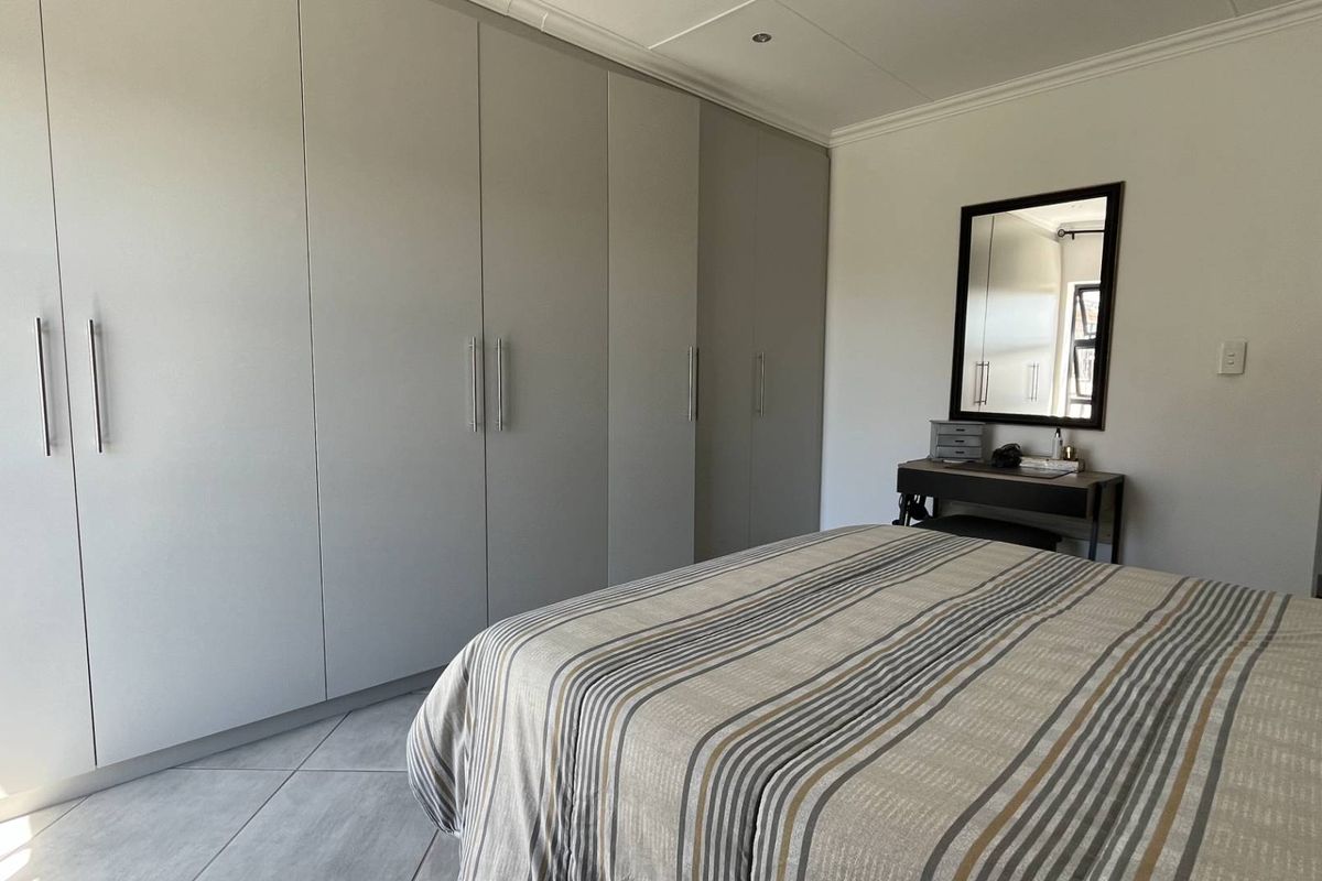 A well-maintained bedroom featuring extensive floor-to-ceiling built-in cabinetry and neutral tiled flooring.