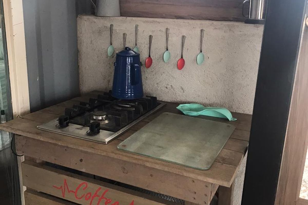 A small, rustic coffee station featuring a built-in gas hob set into a wooden crate-style base.