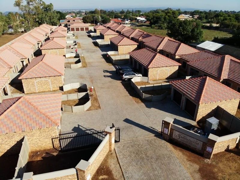 Aerial view of a townhouse complex featuring facebrick units with tiled roofs, paved driveways, and secure gated access.