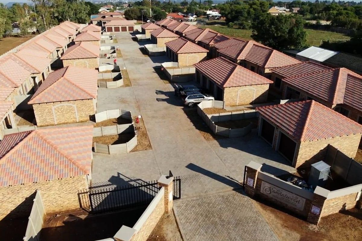Aerial view of a townhouse complex featuring facebrick units with tiled roofs, paved driveways, and secure gated access.
