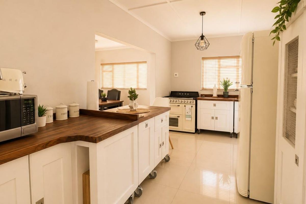 A bright, well-maintained kitchen featuring white cabinetry, warm wooden countertops, tiled flooring, and a classic freestanding oven.