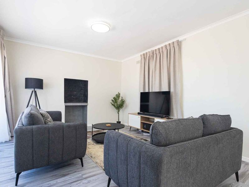 A bright and well-maintained living room featuring laminate flooring and a built-in fireplace, offering a comfortable and inviting space.