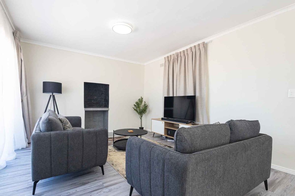 A bright and well-maintained living room featuring laminate flooring and a built-in fireplace, offering a comfortable and inviting space.