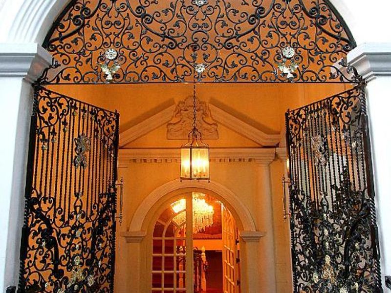 Grand entrance featuring ornate wrought iron gates, arched stone architectural detailing, and polished marble flooring leading into the main foyer.