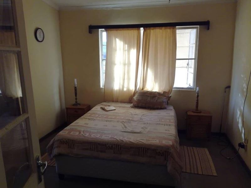 A simple bedroom featuring a window with curtain rod and basic interior finishes, suitable for renovation or modernization.