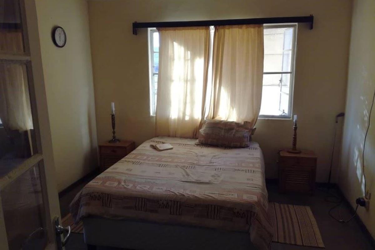 A simple bedroom featuring a window with curtain rod and basic interior finishes, suitable for renovation or modernization.
