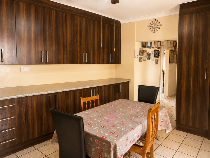 A functional kitchen featuring dark wood-grain cabinetry, ample counter space, and tiled flooring, providing a practical layout for daily meal preparation.