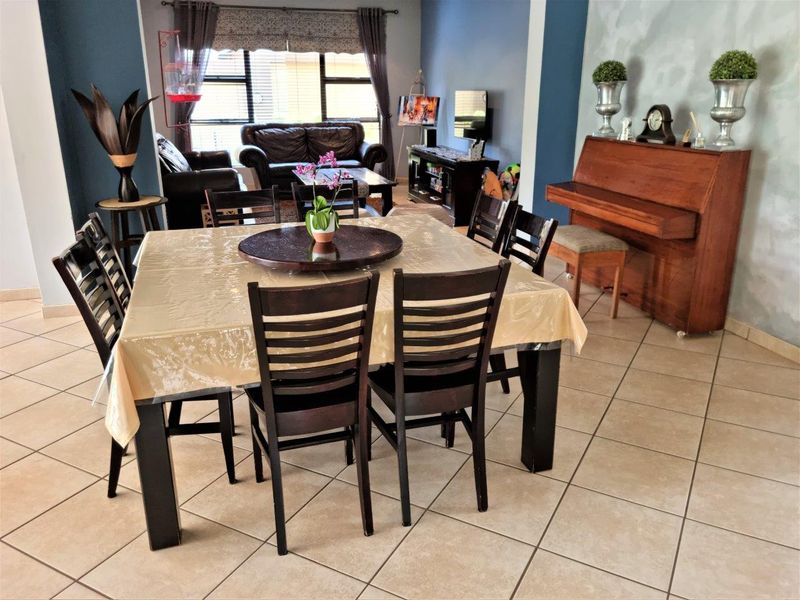 Spacious open-plan living and dining area featuring neutral tiled flooring and large windows, providing a versatile layout for family living and entertaining.