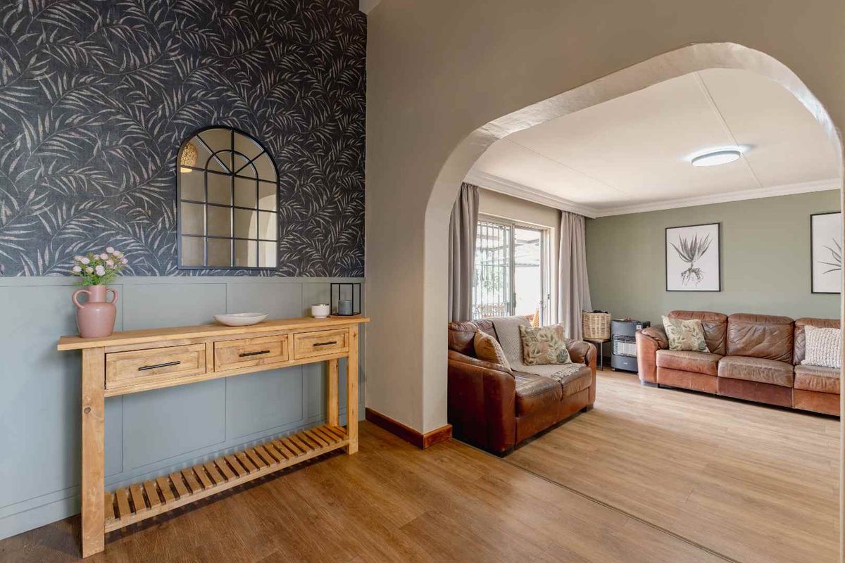A well-maintained living area featuring a decorative archway, wainscoting, and laminate flooring, creating a warm and inviting transition between spaces.