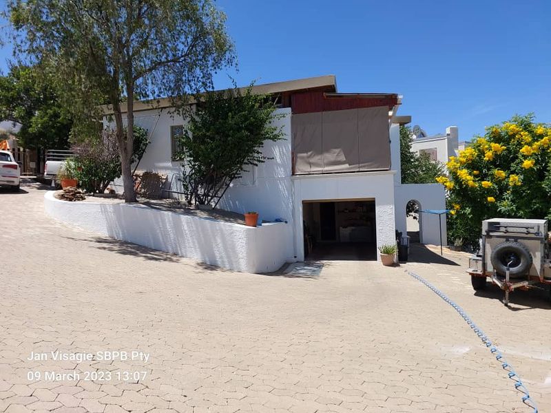 Front exterior view of the property featuring a paved driveway, integrated garage, and a raised garden area with a retaining wall.