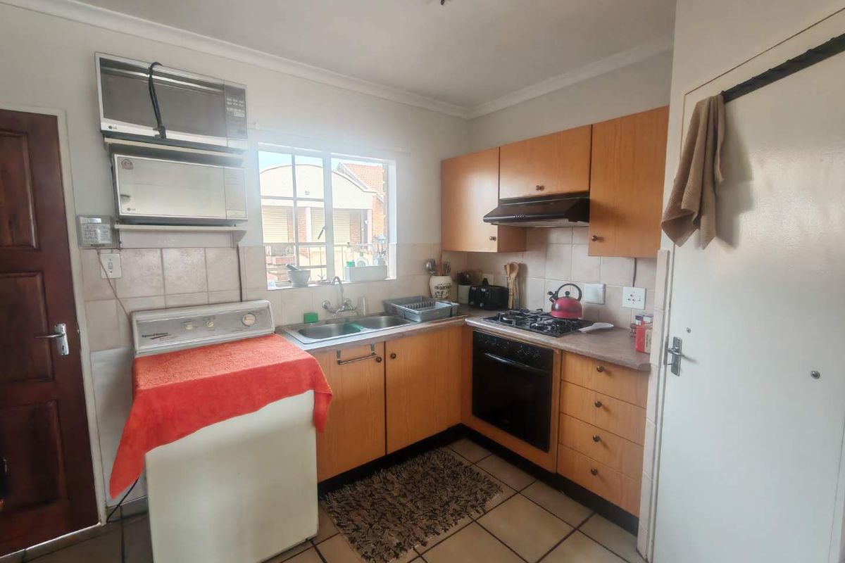 A functional kitchen featuring wood-finish cabinetry, a built-in oven, gas hob, extractor fan, and double-basin sink with tiled splashbacks.