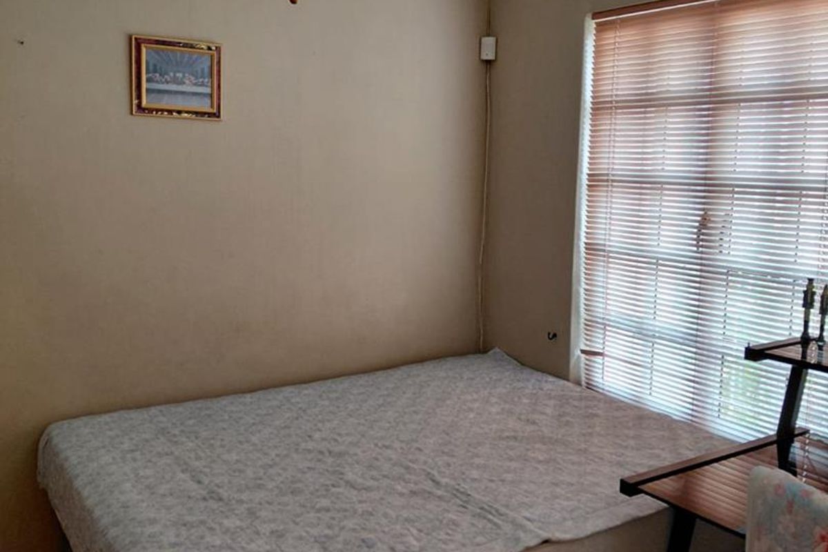 A functional bedroom featuring laminate flooring, crown molding, a ceiling fan, and window blinds.