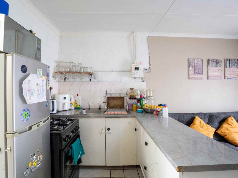 Open plan kitchen area featuring basic cabinetry, a gas stove, stainless steel sink, and a breakfast bar counter connecting to the living space.