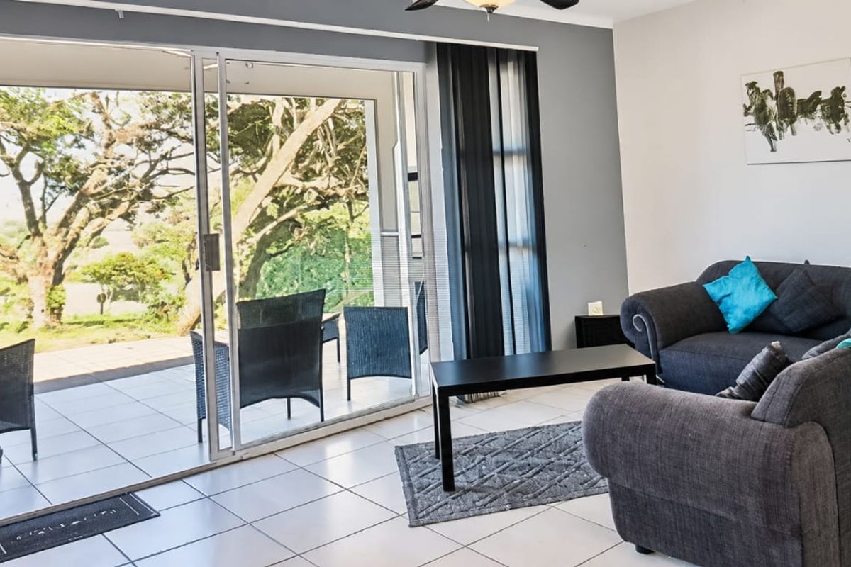 A bright living room featuring tiled flooring and large sliding glass doors that provide seamless access to the outdoor patio area.
