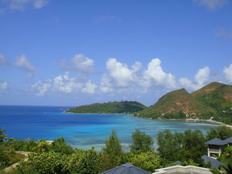 A scenic elevated view overlooking the turquoise coastal waters, lush green hills, and tropical landscape surrounding the property.