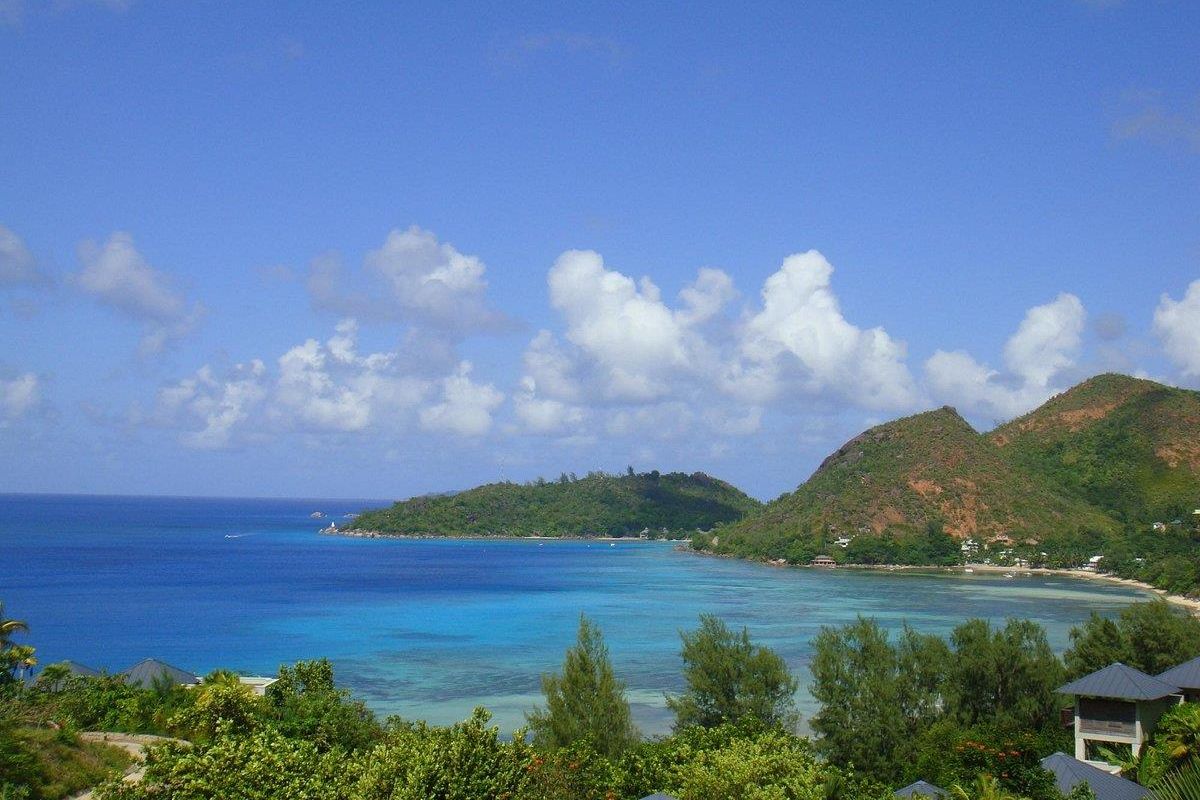 A scenic elevated view overlooking the turquoise coastal waters, lush green hills, and tropical landscape surrounding the property.