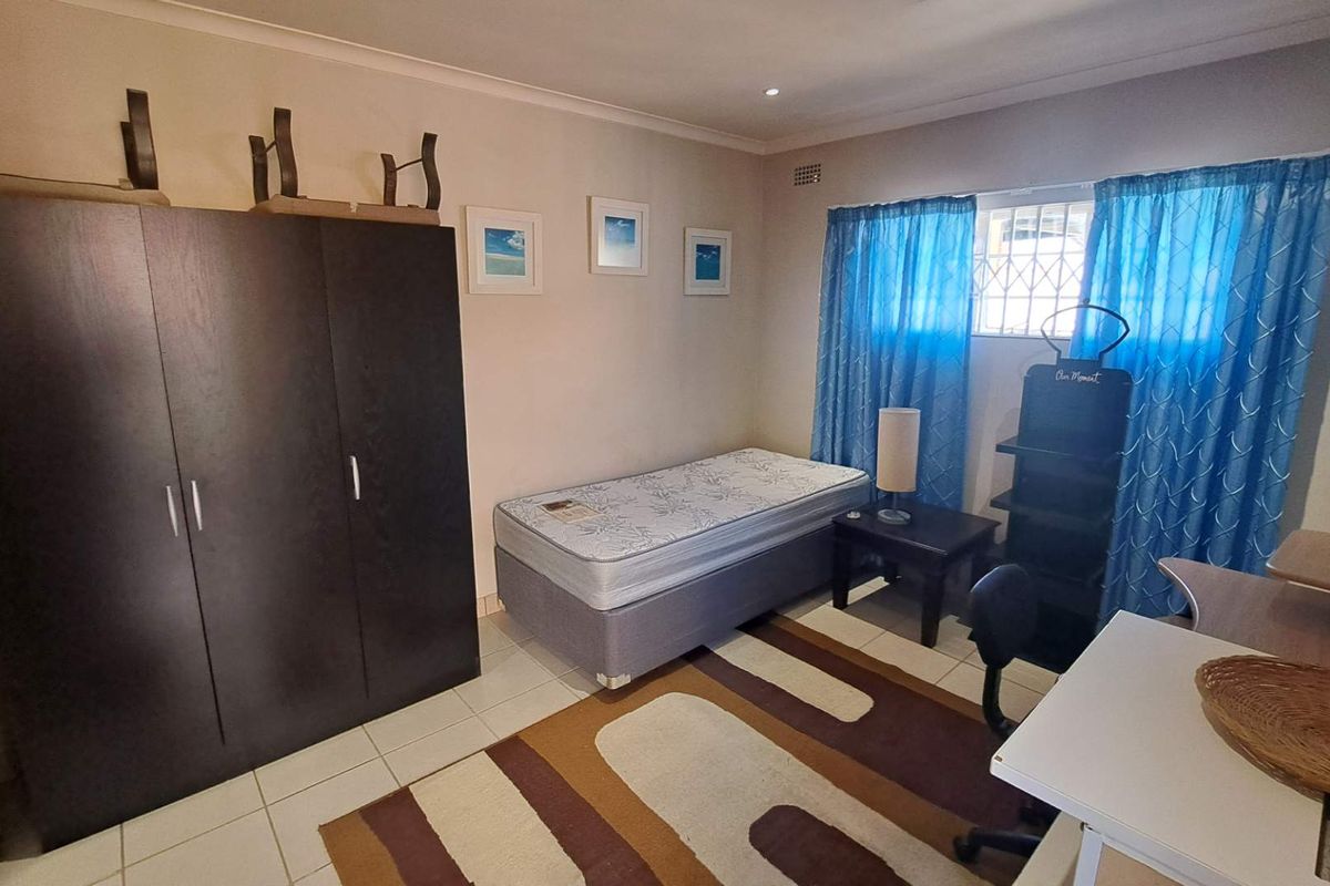 A functional bedroom featuring tiled flooring, a built-in wardrobe, and a window fitted with a security gate.