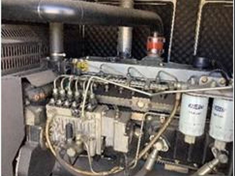 A close-up view of a stationary industrial diesel generator unit, showing the engine block, fuel filters, and exhaust infrastructure.