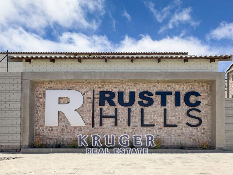 The front entrance facade of the Rustic Hills townhouse complex, featuring brick masonry, tiled roofing, and secure perimeter fencing.