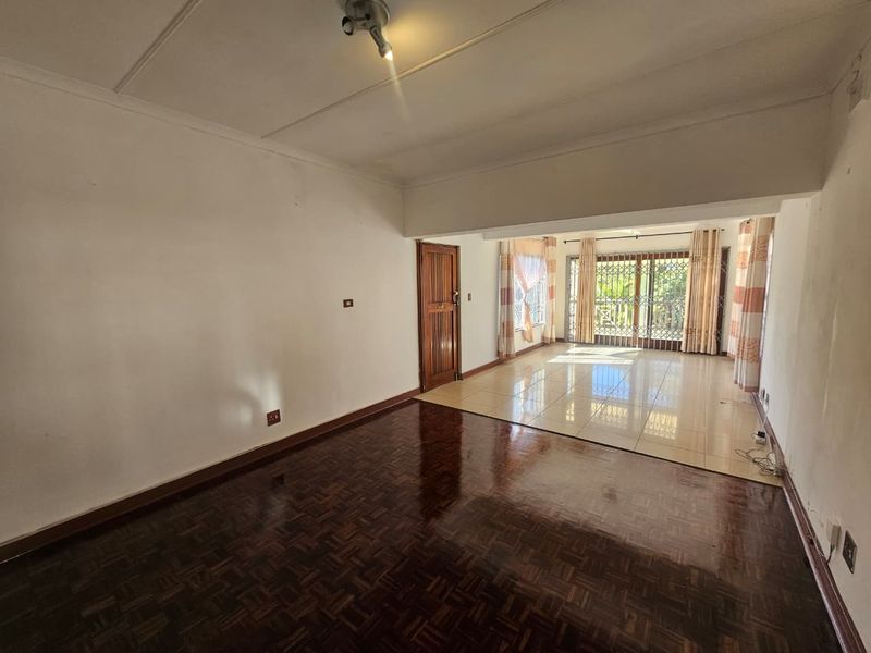 Spacious open-plan living area featuring a combination of parquet and tiled flooring, with direct access to an outdoor space through a security gate.
