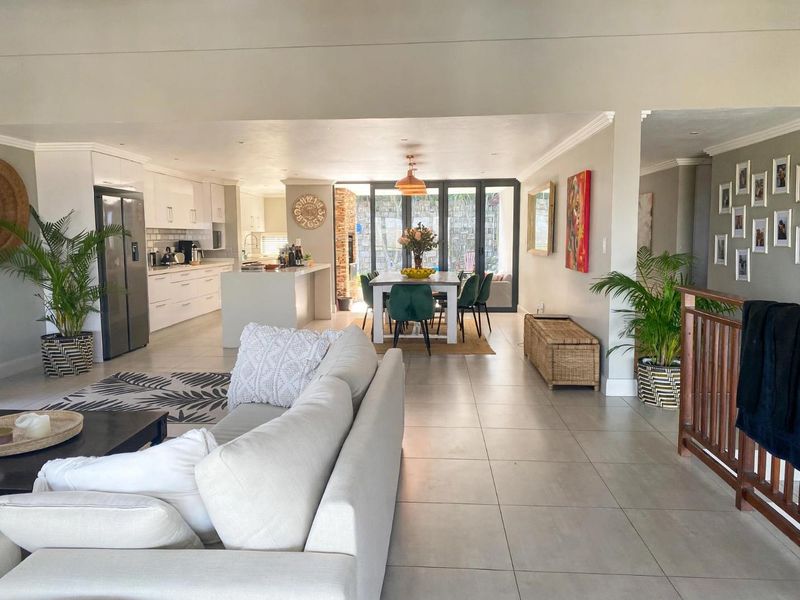 Spacious open-plan living area featuring a modern kitchen with island, tiled floors, and large sliding doors leading to the outdoor space.