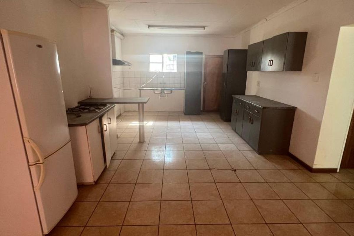 A functional kitchen space featuring tiled flooring, built-in cabinetry, and a basic layout with integrated stove and sink area.