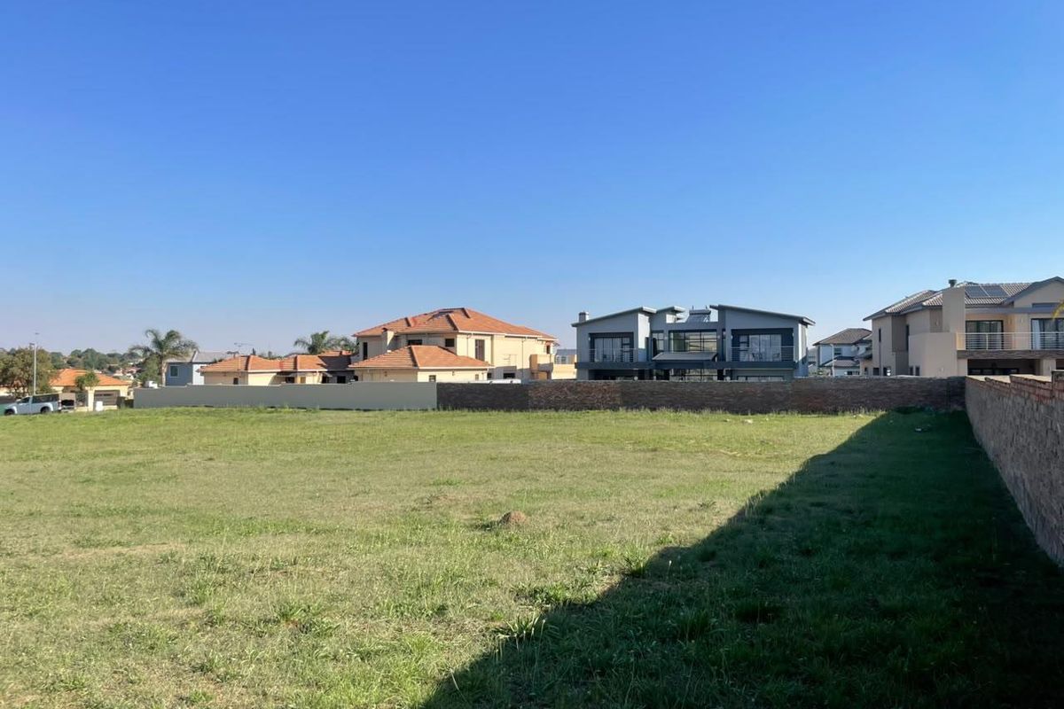 A vacant residential plot featuring perimeter boundary walls, situated in a developed neighborhood with surrounding established homes.