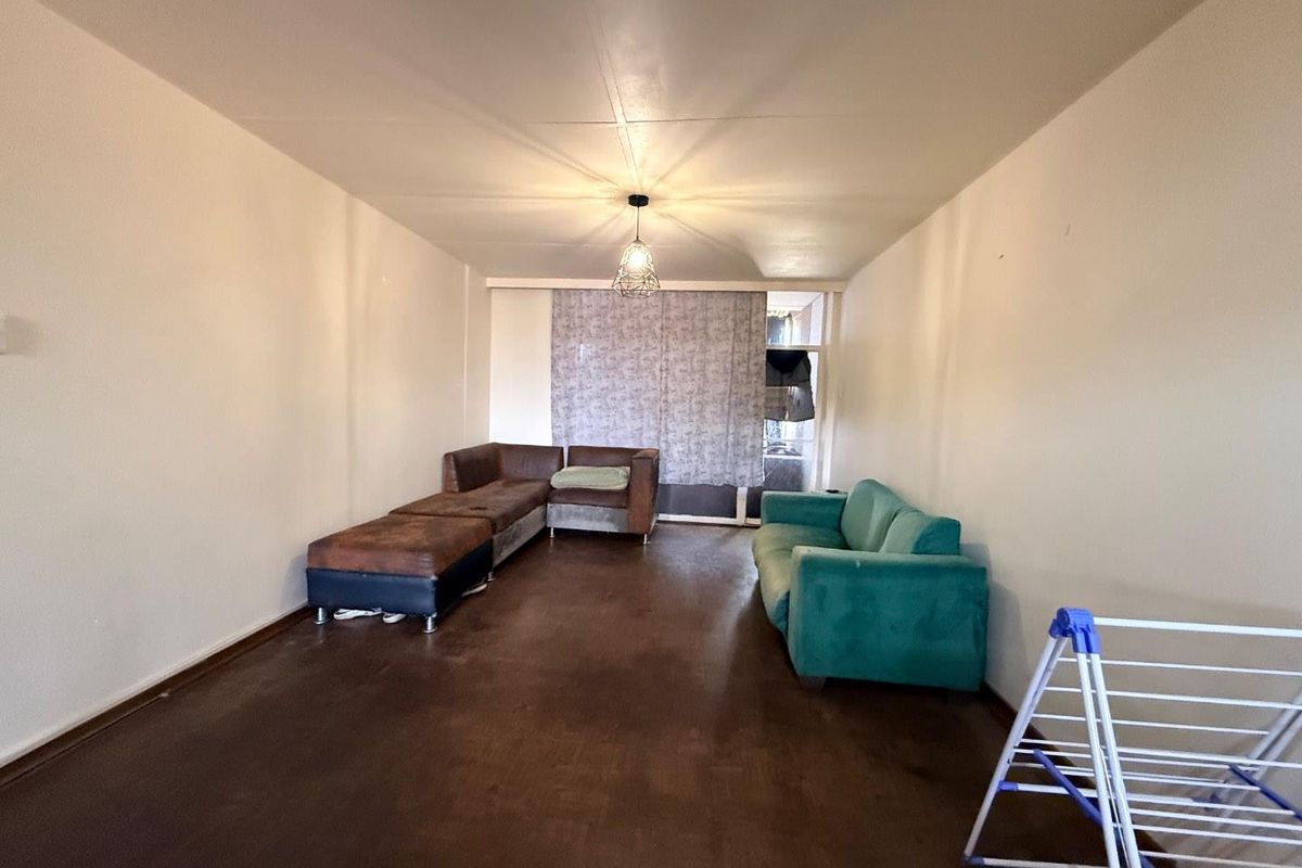 A spacious living room featuring dark flooring and neutral walls, offering a blank canvas for potential renovation and interior design updates.