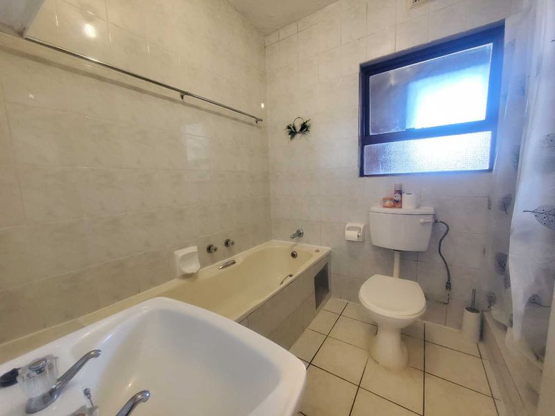 A dated bathroom featuring a bathtub, toilet, and tiled finishes, offering potential for modernization and renovation.