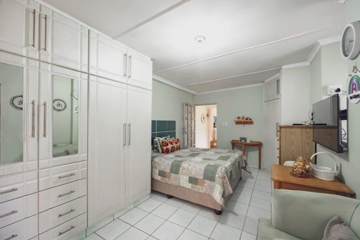 A functional bedroom featuring extensive built-in cabinetry, tiled flooring, and neutral wall finishes, offering practical storage and a comfortable living space.